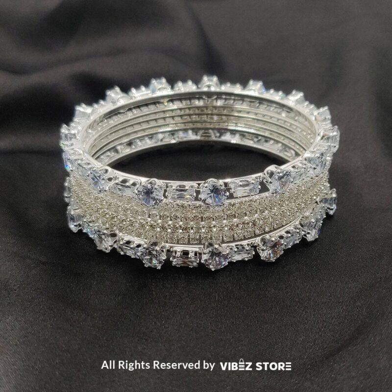 Silver-toned crystal bangle set with intricate detailing on a black background