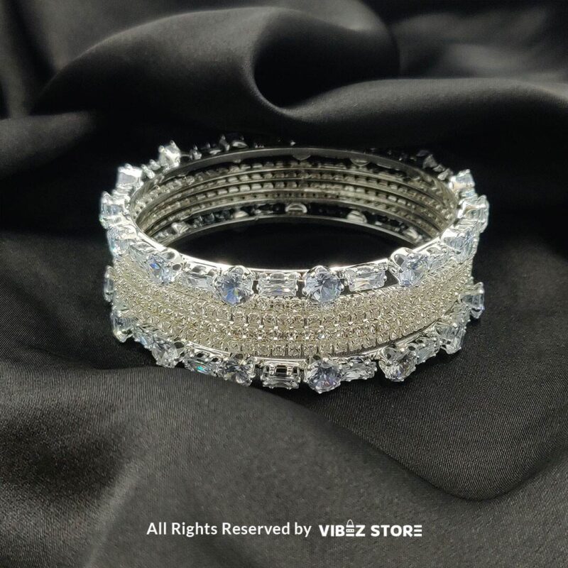 Silver-toned crystal bangle set with intricate detailing on a black background