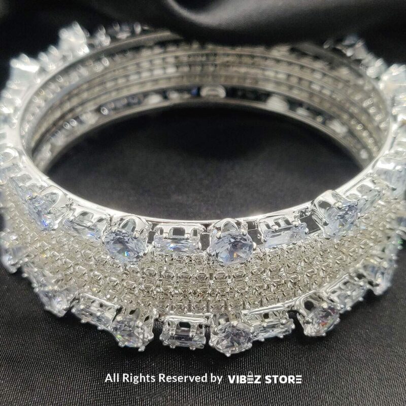 Silver-toned crystal bangle set with intricate detailing on a black background