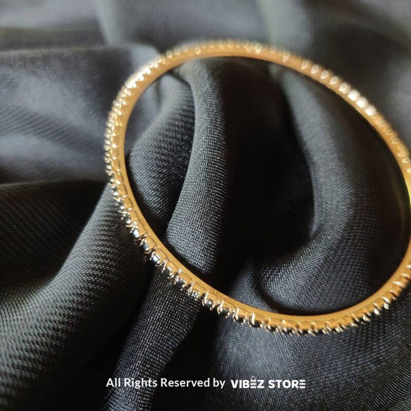 Multi-layer gold bangle set with black crystal accents on a black fabric background