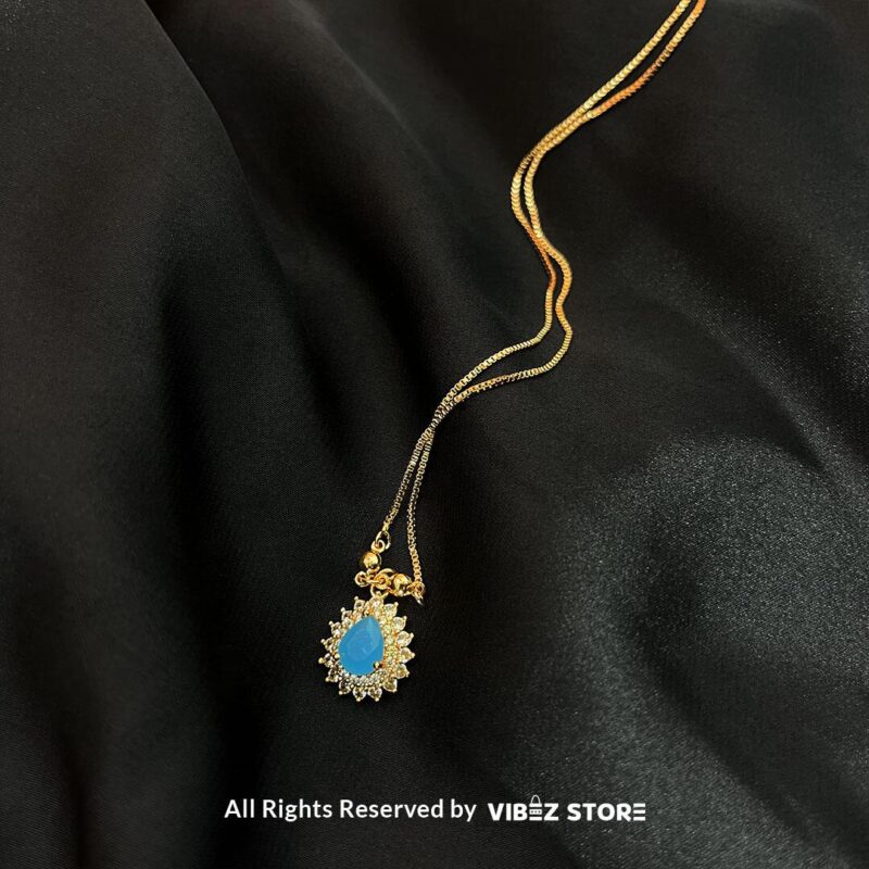 Teardrop Crystal Locket in amber, emerald, and turquoise colors with gold chains on a black background