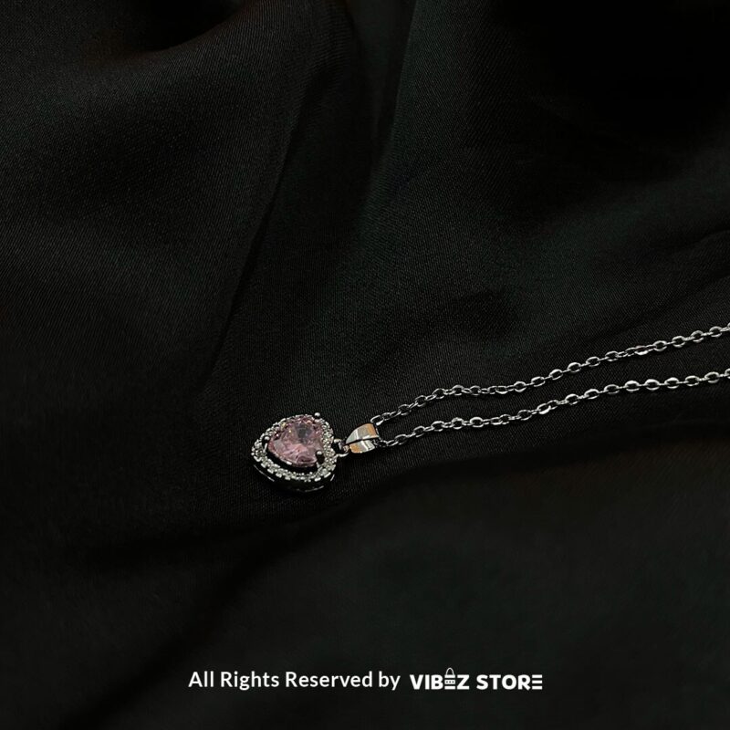 Heart-Shaped Pink Gemstone Locket with silver-tone chain on a black background