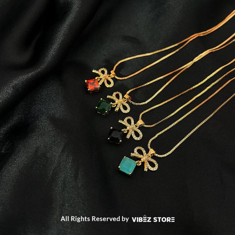 Bow-adorned Square Gemstone Locket in red, green, black, and turquoise colors with gold chains on a black background