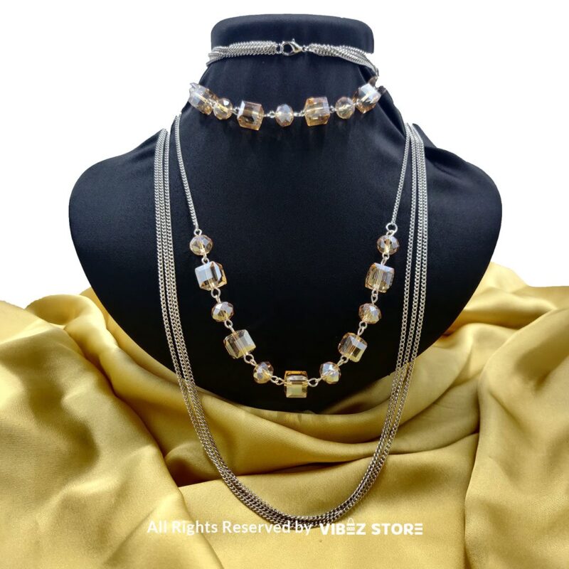 Elegant crystal cube and silver-tone chain necklace set on a black bust with yellow fabric background