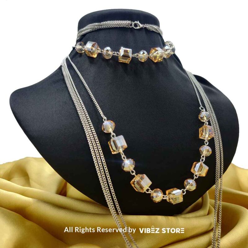 Elegant crystal cube and silver-tone chain necklace set on a black bust with yellow fabric background