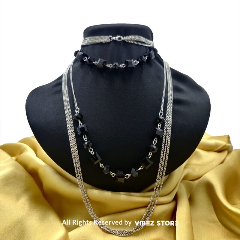 Elegant crystal cube and silver-tone chain necklace set on a black bust with yellow fabric background