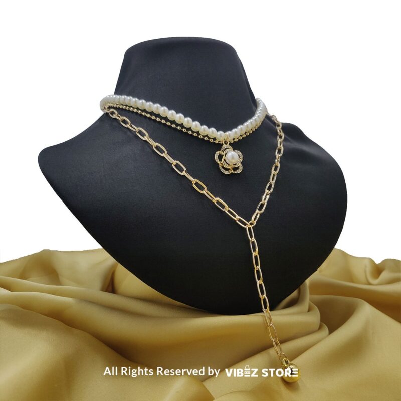 Pearl and gold chain layered necklace with flower pendant displayed on black bust