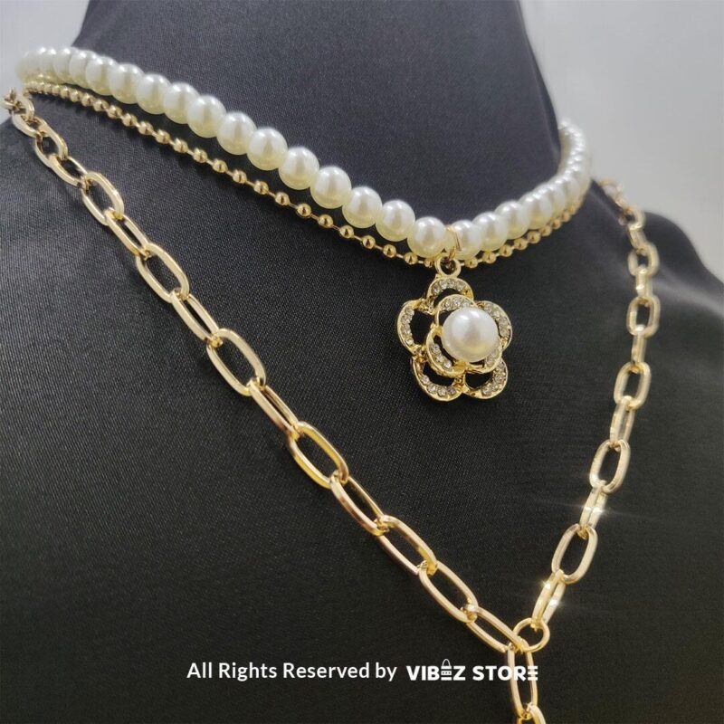 Pearl and gold chain layered necklace with flower pendant displayed on black bust