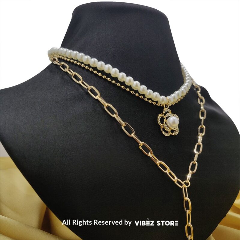 Pearl and gold chain layered necklace with flower pendant displayed on black bust