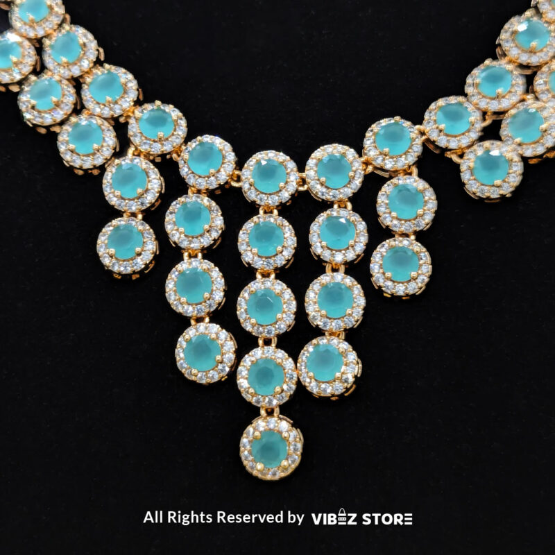 Gold-tone jewelry set with aqua blue gemstones, including a necklace, earrings, bracelet, and ring, elegantly displayed by Vibez Store.