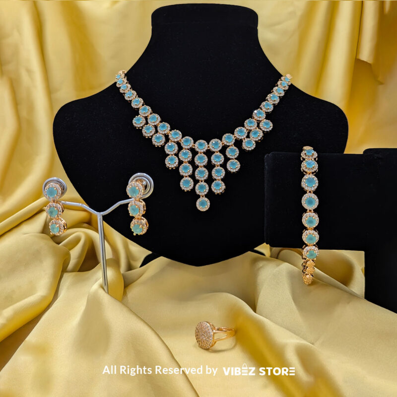 Gold-tone jewelry set with aqua blue gemstones, including a necklace, earrings, bracelet, and ring, elegantly displayed by Vibez Store.