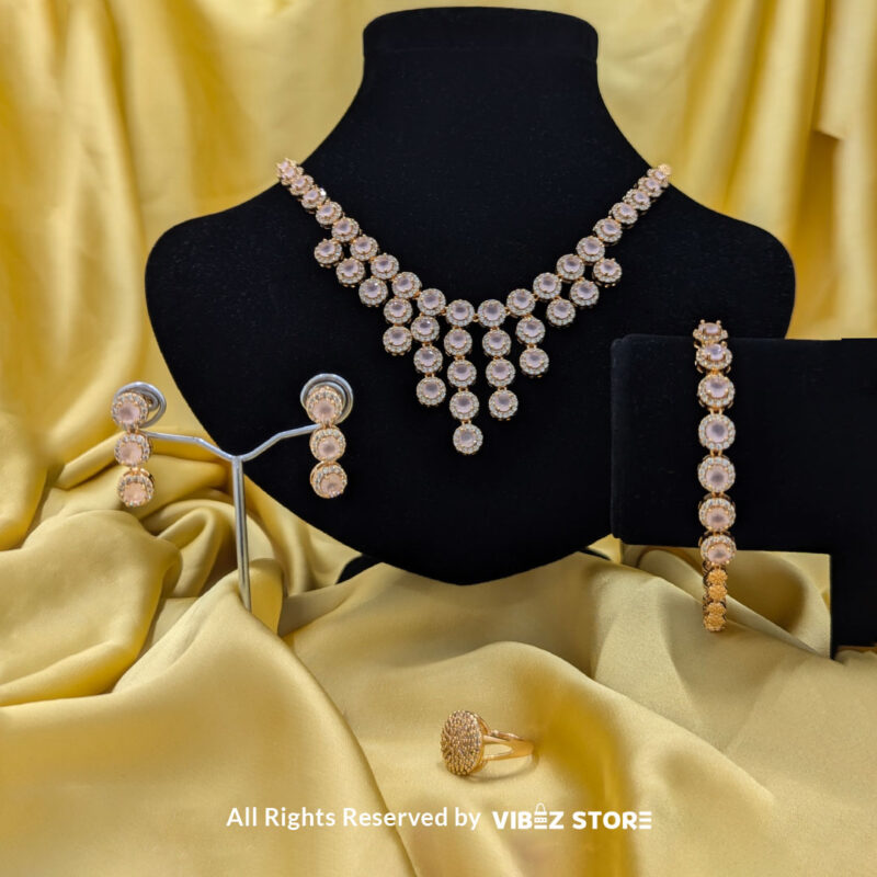 Gold-tone jewelry set with rose quartz-inspired stones, including a necklace, earrings, bracelet, and ring, elegantly displayed by Vibez Store.