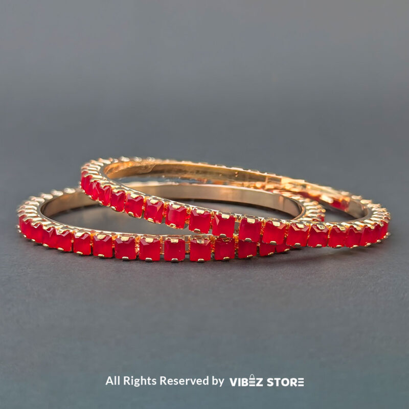 Rose gold bangles set with vibrant red crystals for festive and party wear.