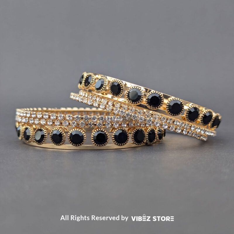 Gold-plated bangle set with black stones and crystal embellishments on a black background