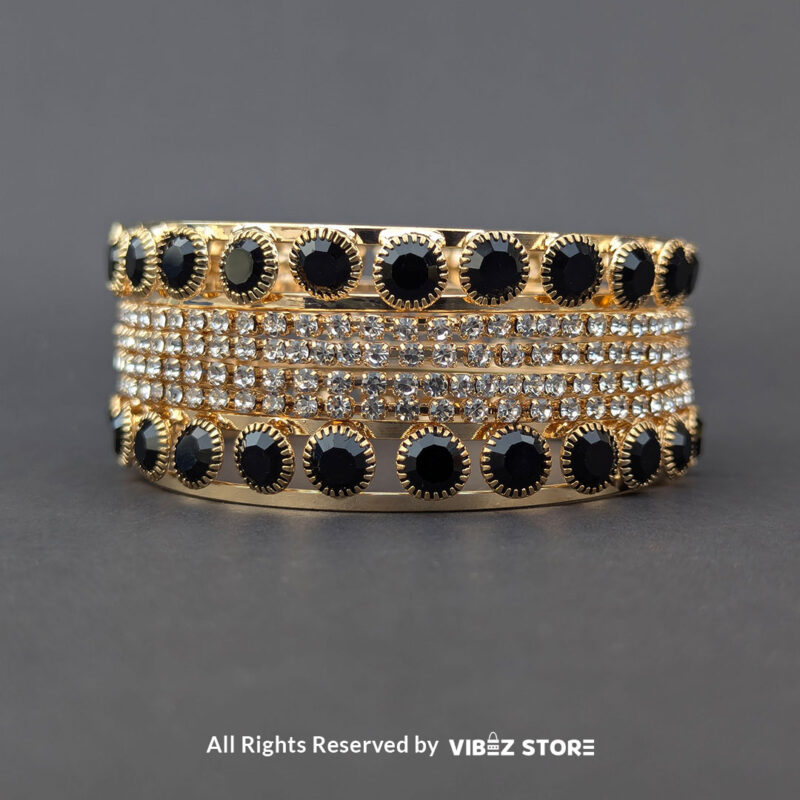 Gold-plated bangle set with black stones and crystal embellishments on a black background