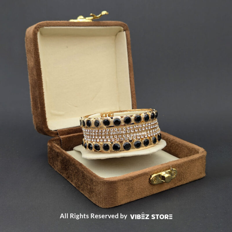 Gold-plated bangle set with black stones and crystal embellishments on a black background