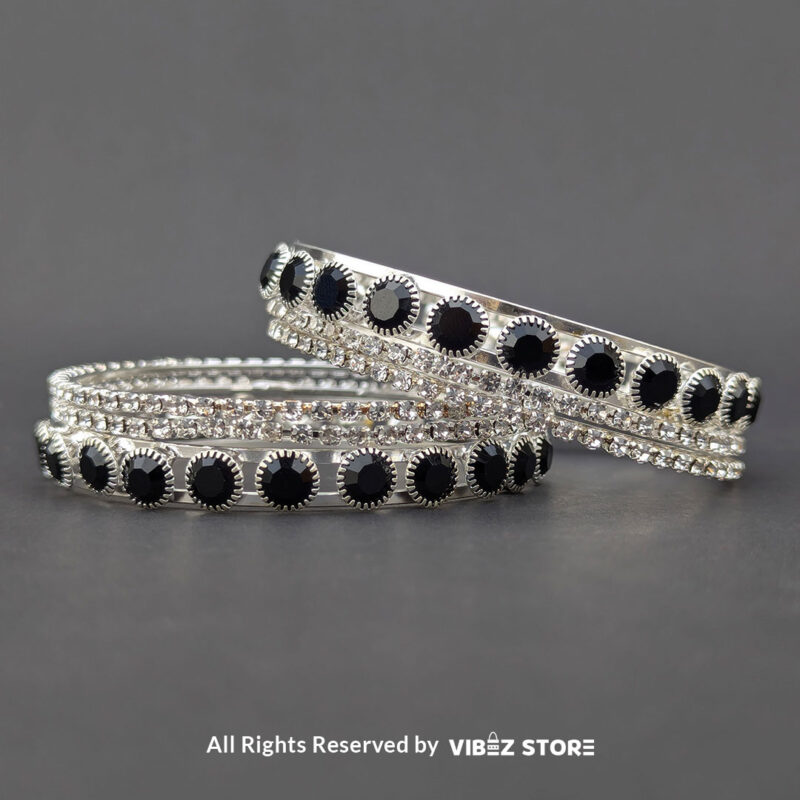 Silver-tone bangle set with black stones and crystal accents on a black fabric background