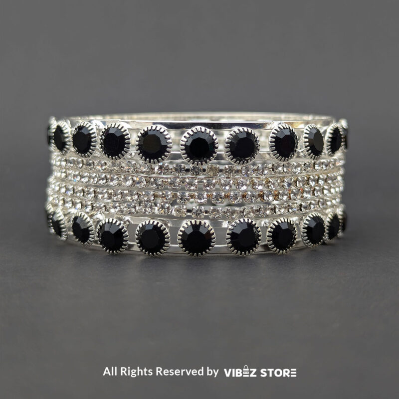 Silver-tone bangle set with black stones and crystal accents on a black fabric background