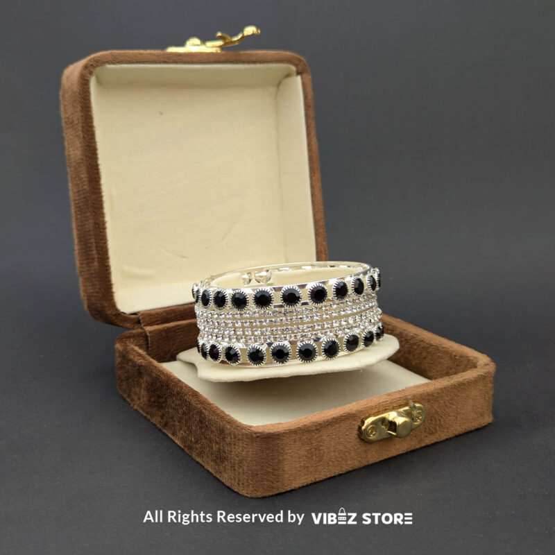 Silver-tone bangle set with black stones and crystal accents on a black fabric background