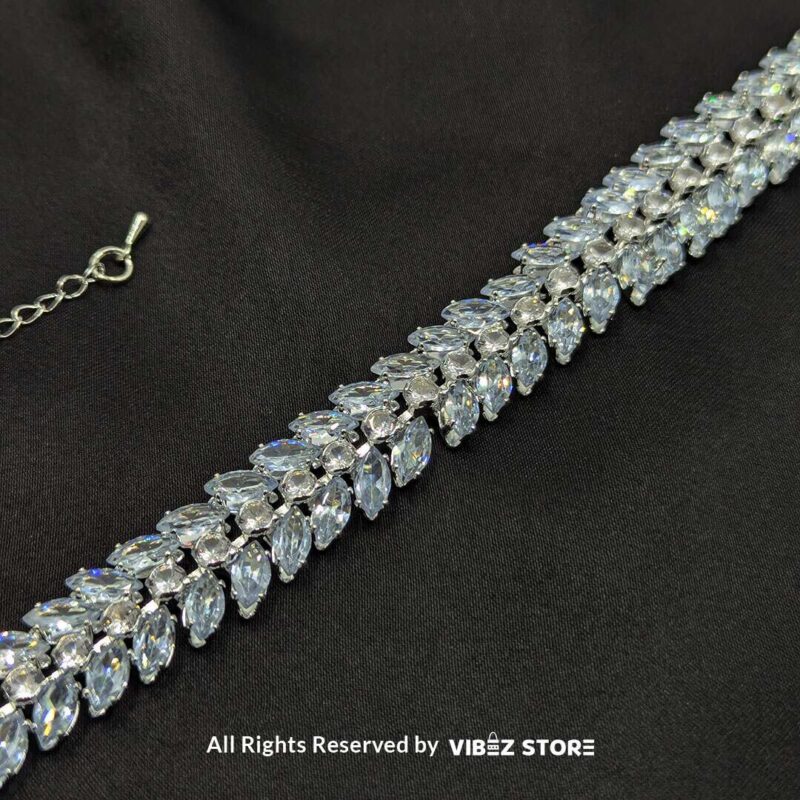 Silver-tone double row crystal bracelet with shimmering marquise-cut stones on a black fabric background.

