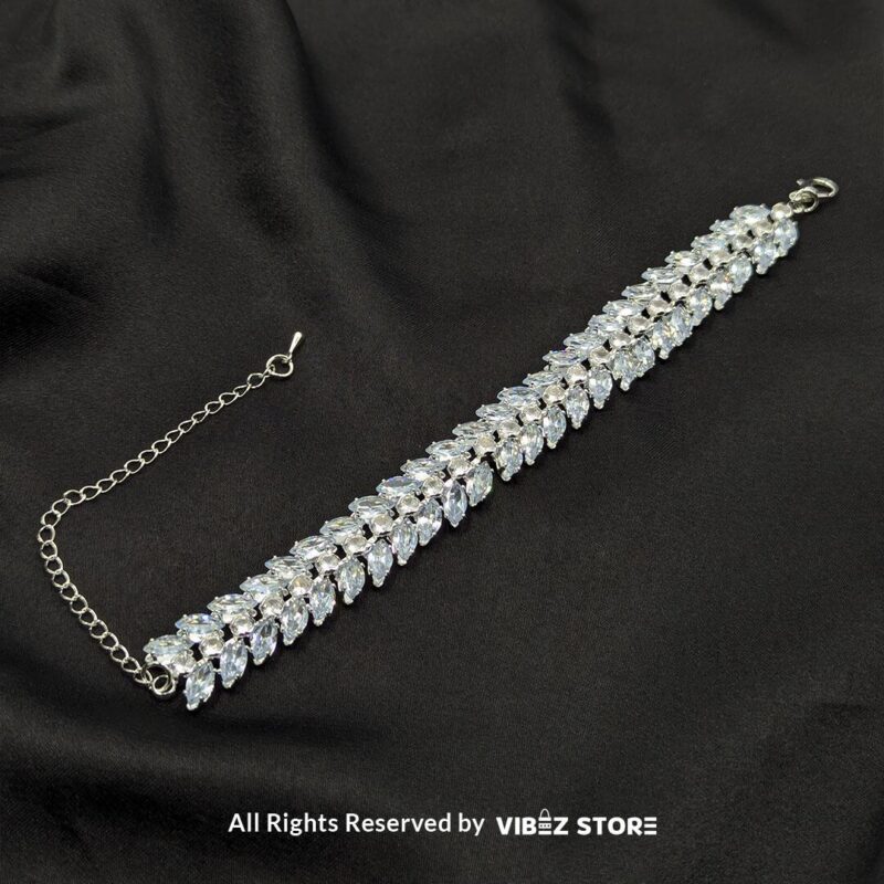 Silver-tone double row crystal bracelet with shimmering marquise-cut stones on a black fabric background.

