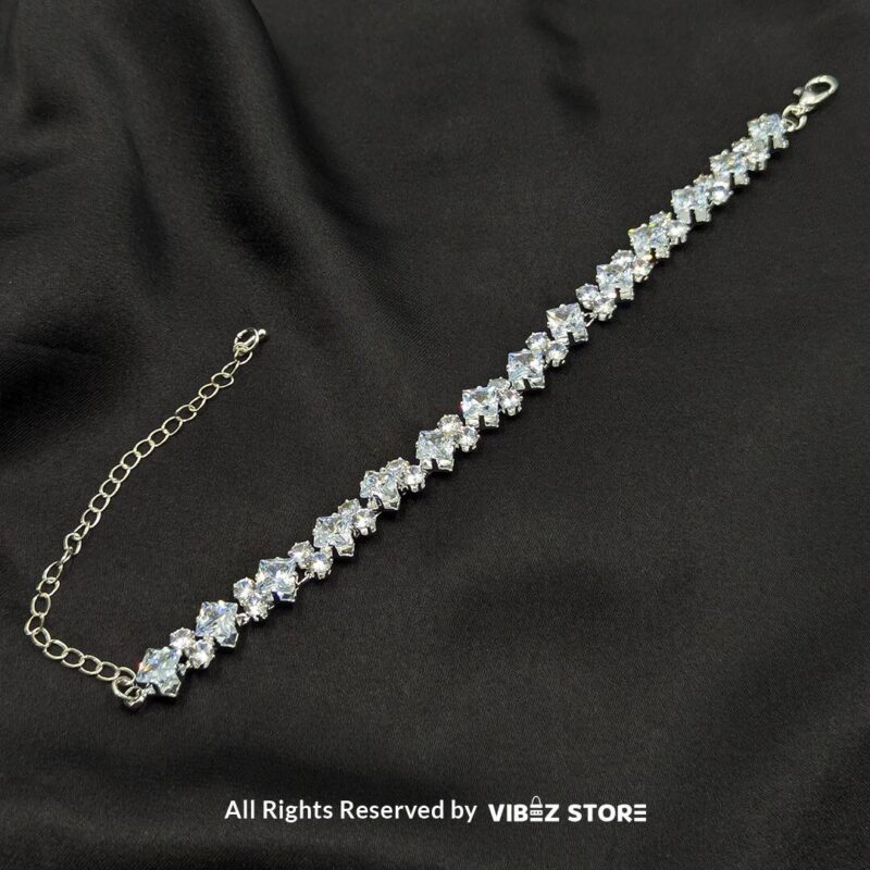 Silver-tone solitaire crystal bracelet with sparkling stones on a black fabric background.