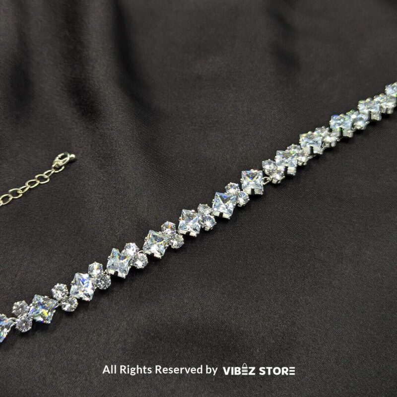 Silver-tone solitaire crystal bracelet with sparkling stones on a black fabric background.