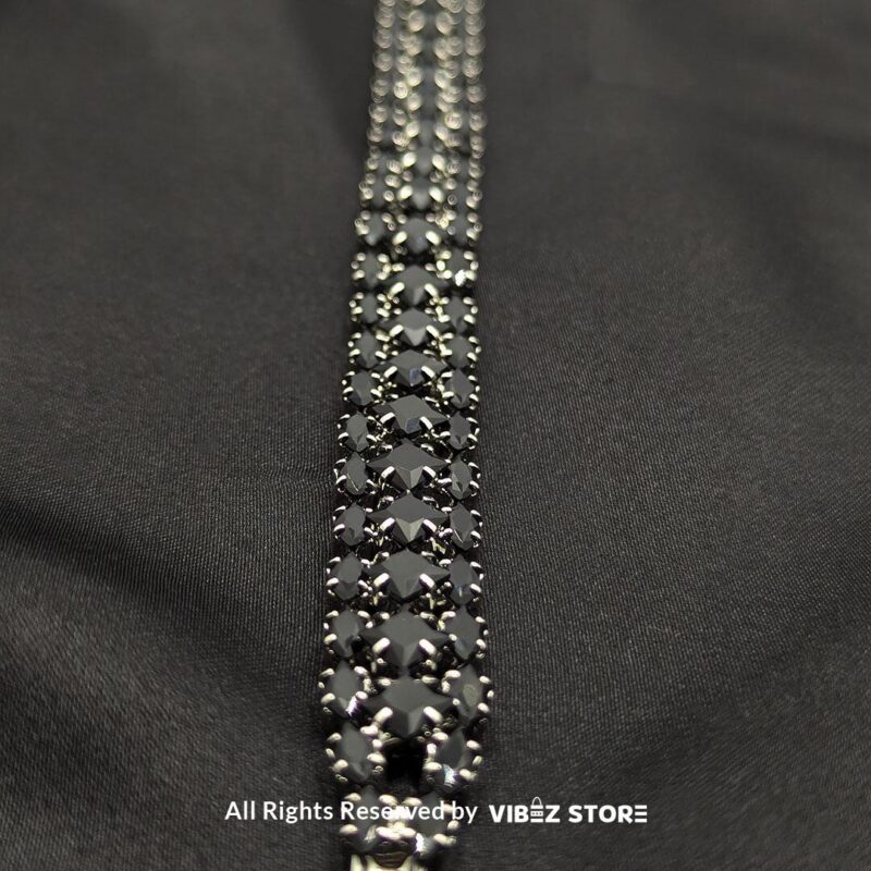 Black stone multi-row bracelet with a silver-tone frame on a black fabric background.