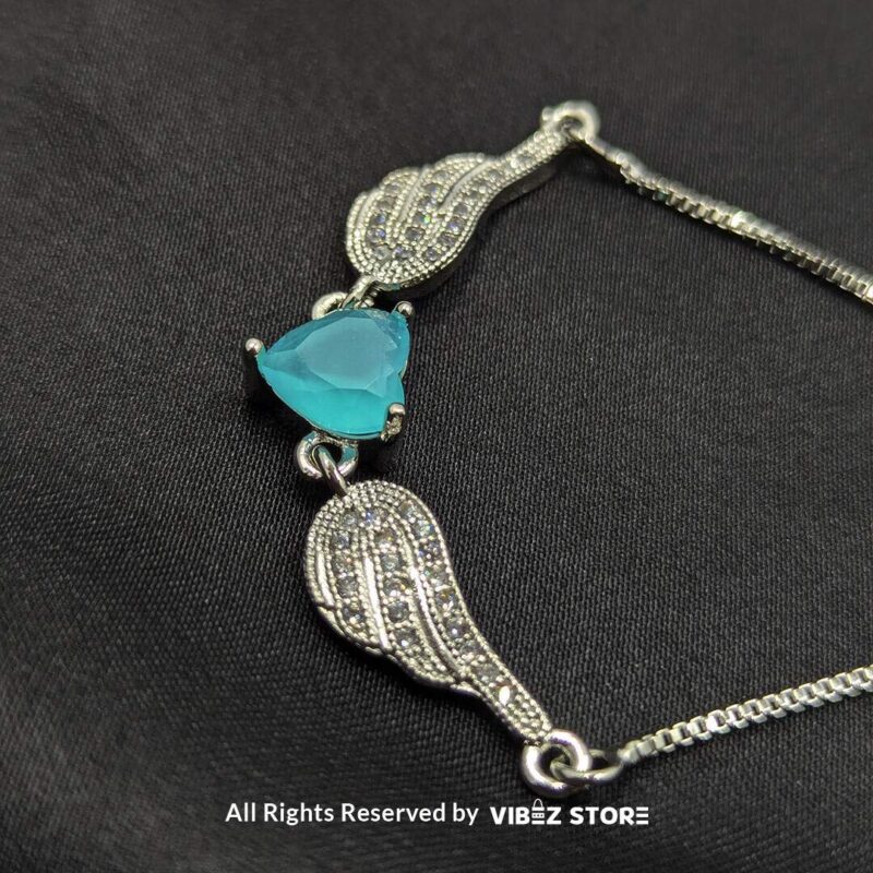 Silver adjustable bracelet with teardrop turquoise stone and intricate detailing on black fabric background