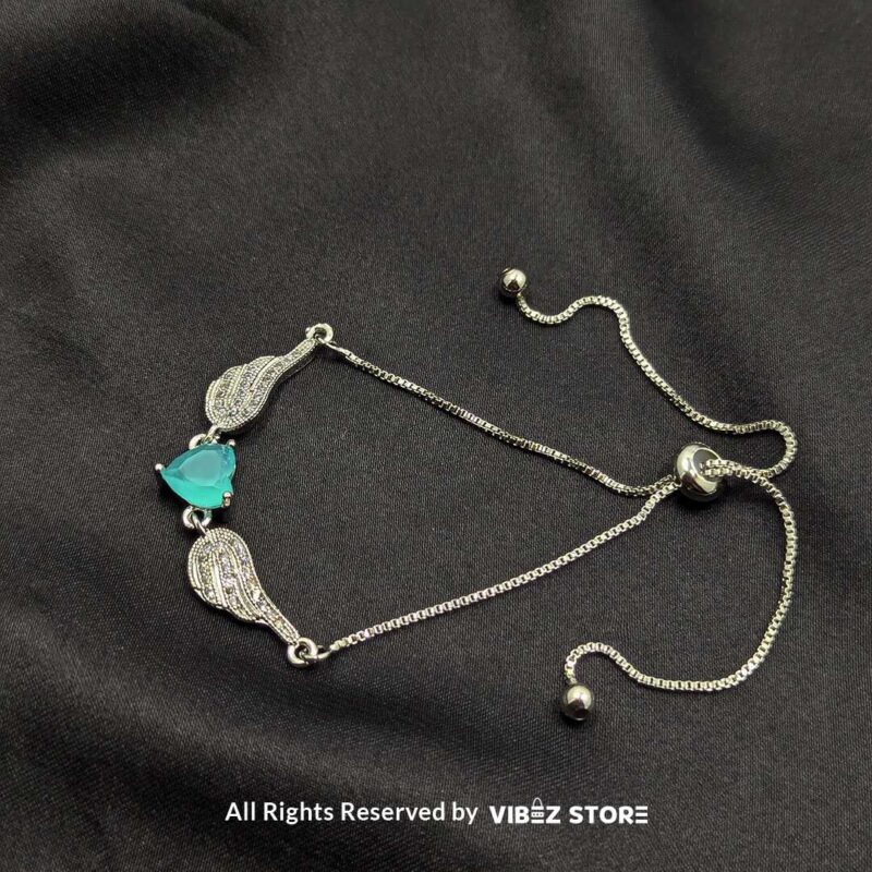 Silver adjustable bracelet with teardrop turquoise stone and intricate detailing on black fabric background