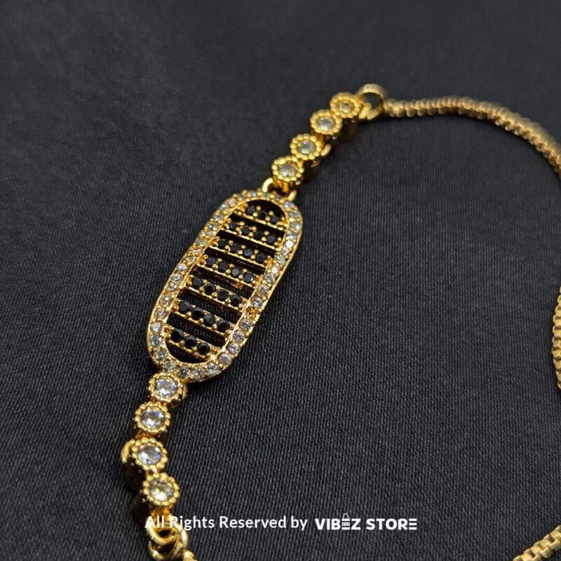 Gold adjustable bracelet with oval crystal centerpiece and adjustable chain on black fabric background