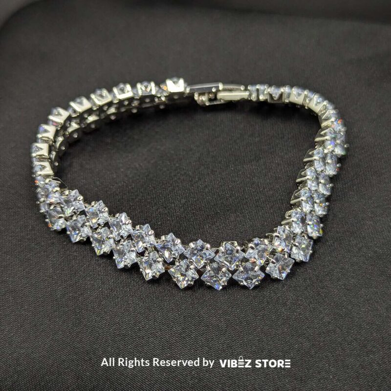 A luxury double-layered silver-tone bracelet with diamond-cut sparkling crystals displayed on a black fabric background.