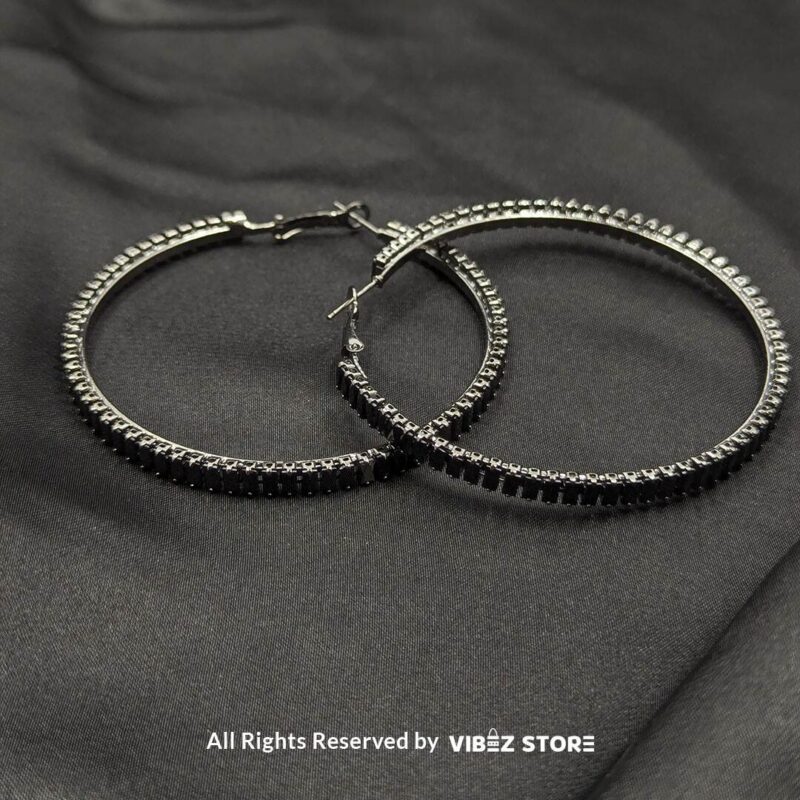 Crystal hoop earrings in gold and black displayed elegantly on a black fabric background.