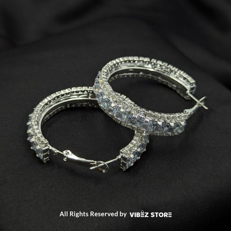 Gold hoop earrings with black crystals and silver hoop earrings with clear crystals displayed against a black fabric background.