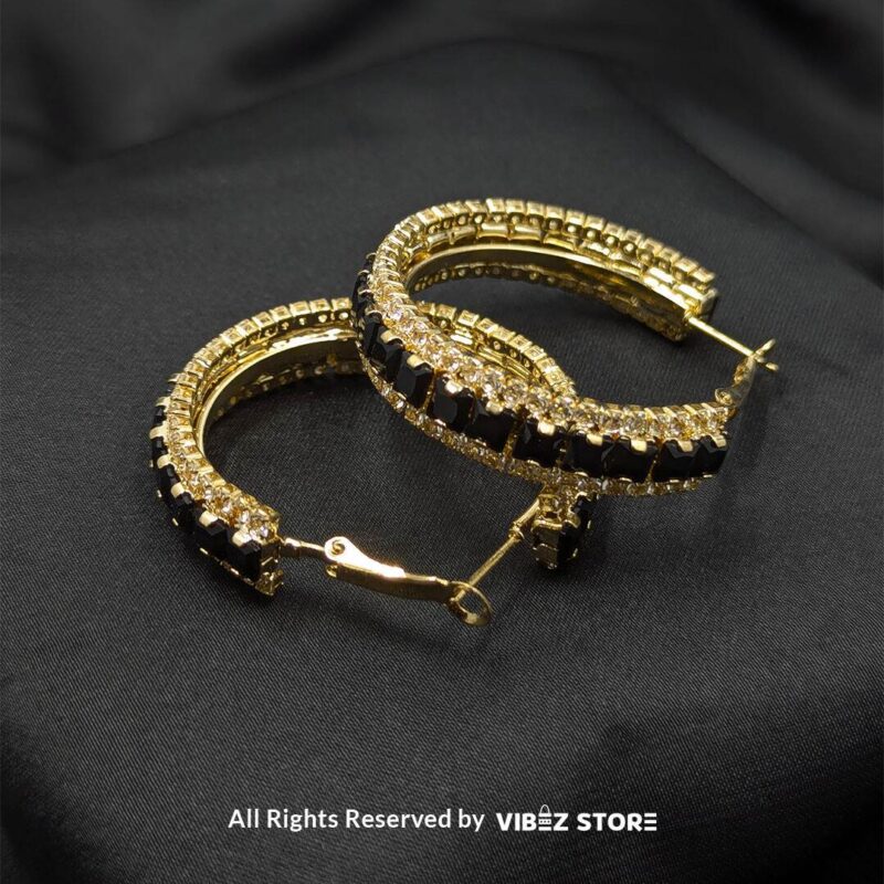 Gold hoop earrings with black crystals and silver hoop earrings with clear crystals displayed against a black fabric background.