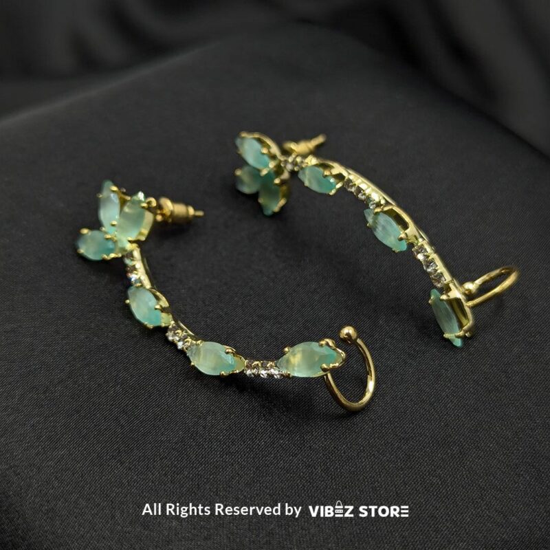 Gold-tone earrings featuring aqua stones and crystal accents, designed in a graceful curved shape, displayed on a black fabric background. 