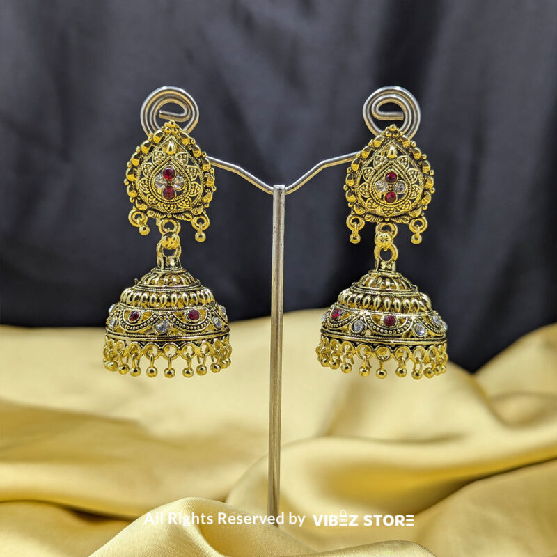 Gold plated antique jhumka earrings with intricate detailing, red stone accents, and bead danglers, perfect for weddings and cultural celebrations.