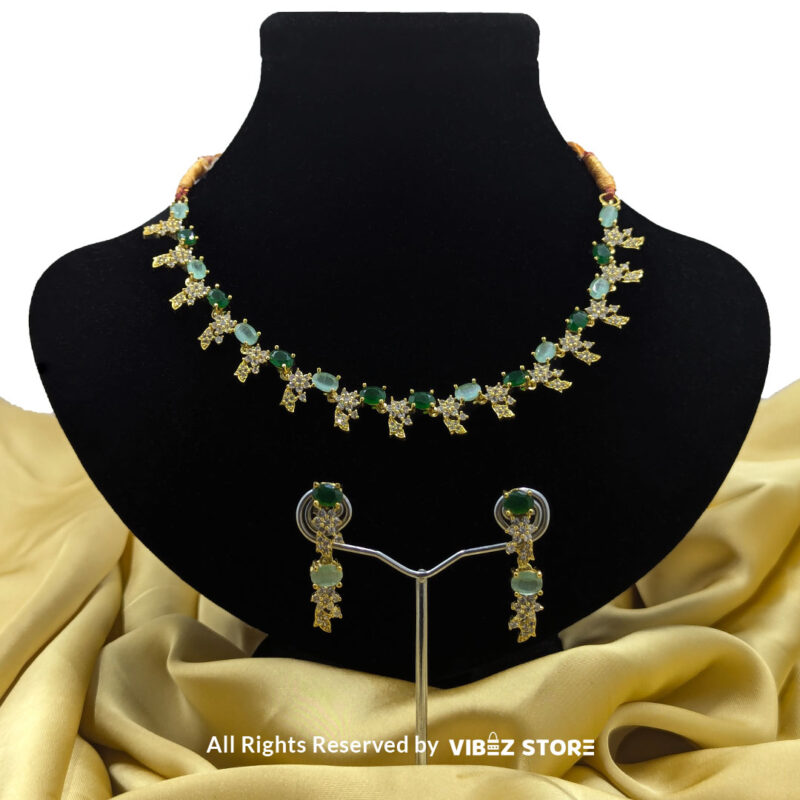 Gold-plated necklace set with vibrant green gemstones and a matching earring pair displayed on a black mannequin, perfect for weddings and formal events.