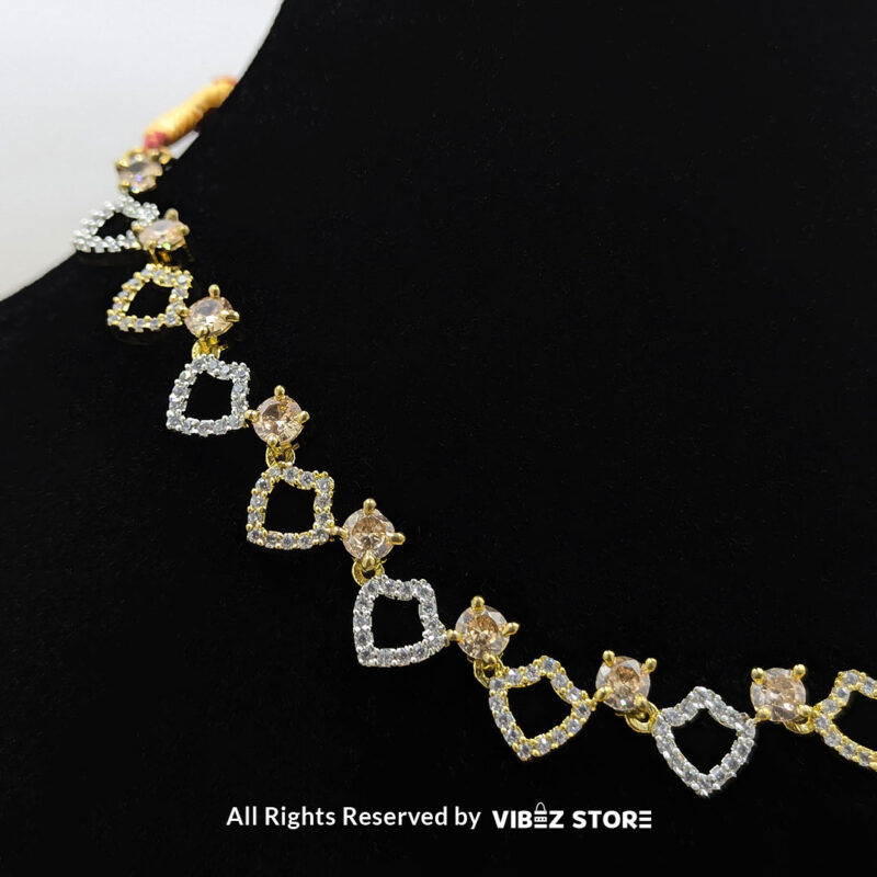 Heart-shaped necklace set with sparkling stones and matching earrings, displayed on a black mannequin with a golden fabric backdrop.