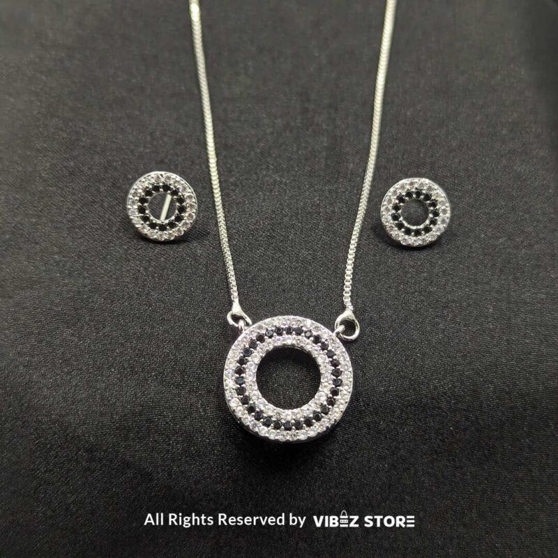 Silver round pendant jewelry set with a delicate chain necklace and matching circular stud earrings, adorned with cubic zirconia stones.

