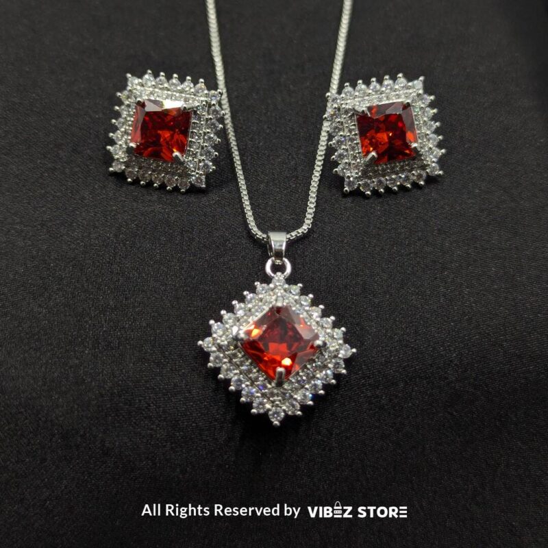 Ruby red square pendant jewelry set featuring a vibrant red gemstone necklace with matching stud earrings, surrounded by sparkling stones.