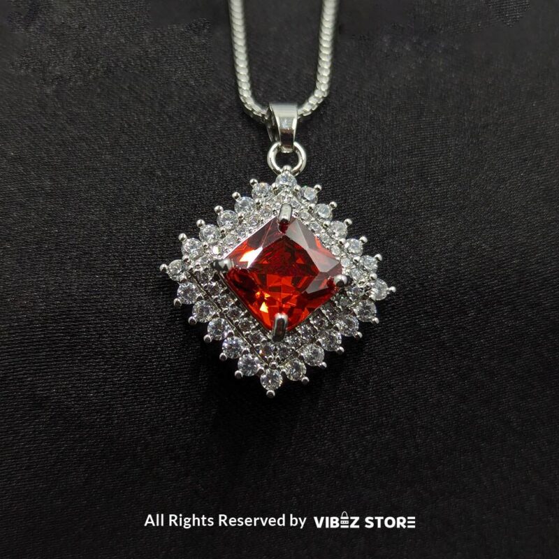 Ruby red square pendant jewelry set featuring a vibrant red gemstone necklace with matching stud earrings, surrounded by sparkling stones.