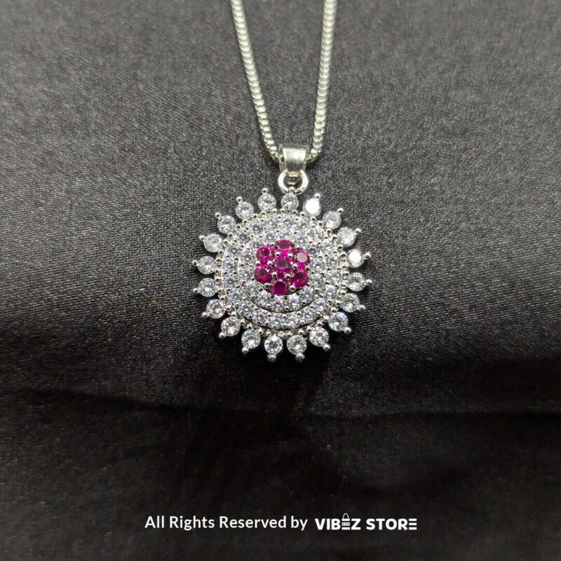 Ruby starburst pendant with matching earrings, featuring shimmering crystals and a vibrant ruby centerpiece, displayed on a sleek black fabric.