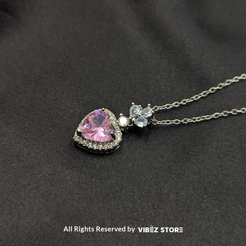 Elegant heart-shaped locket with a pink gemstone and silver floral detailing, perfect for gifting or personal use.