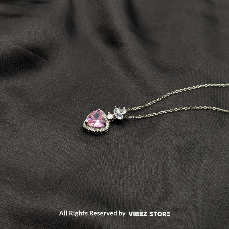 Elegant heart-shaped locket with a pink gemstone and silver floral detailing, perfect for gifting or personal use.