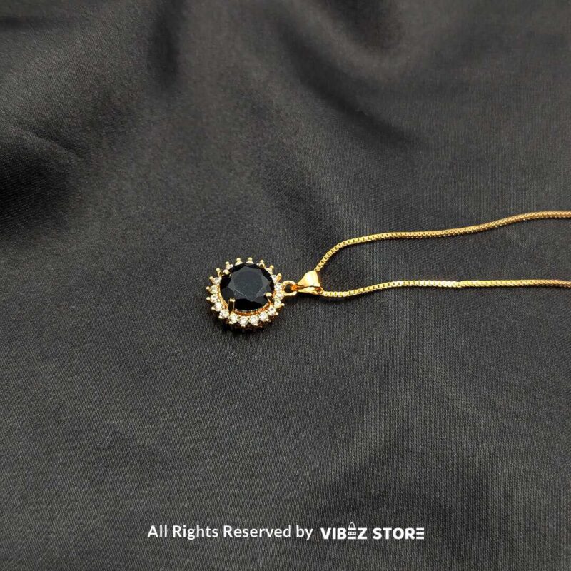 Three round gemstone lockets with crystal halos, displayed on gold-tone and silver-tone chains against a black fabric background.