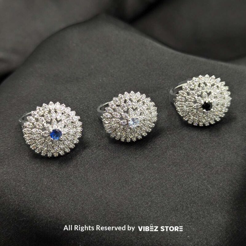 Silver-tone floral rings with crystal accents and central gemstones in sapphire blue, clear crystal, and jet black, beautifully displayed by Vibez Store.