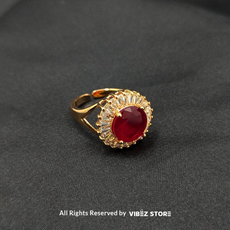 A luxurious gold-tone ring with a ruby-red centerpiece encircled by a sparkling crystal halo, from Vibez Store.