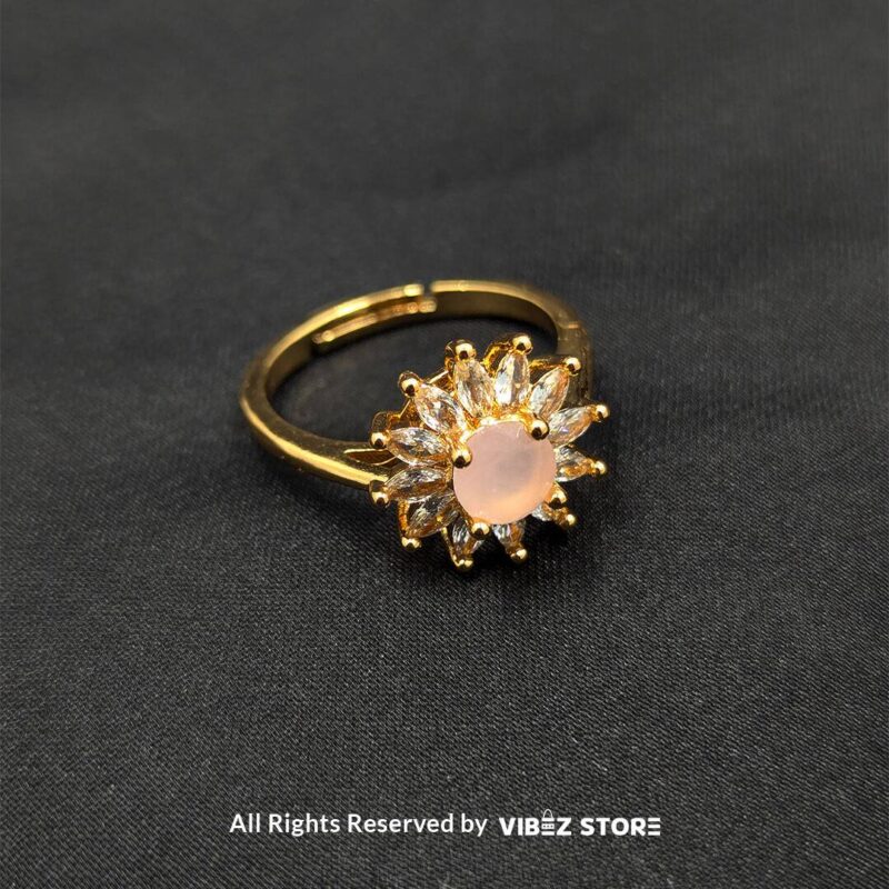 Golden ring with a soft pink center stone and sunburst-style crystal accents, exuding elegance and charm from Vibez Store.