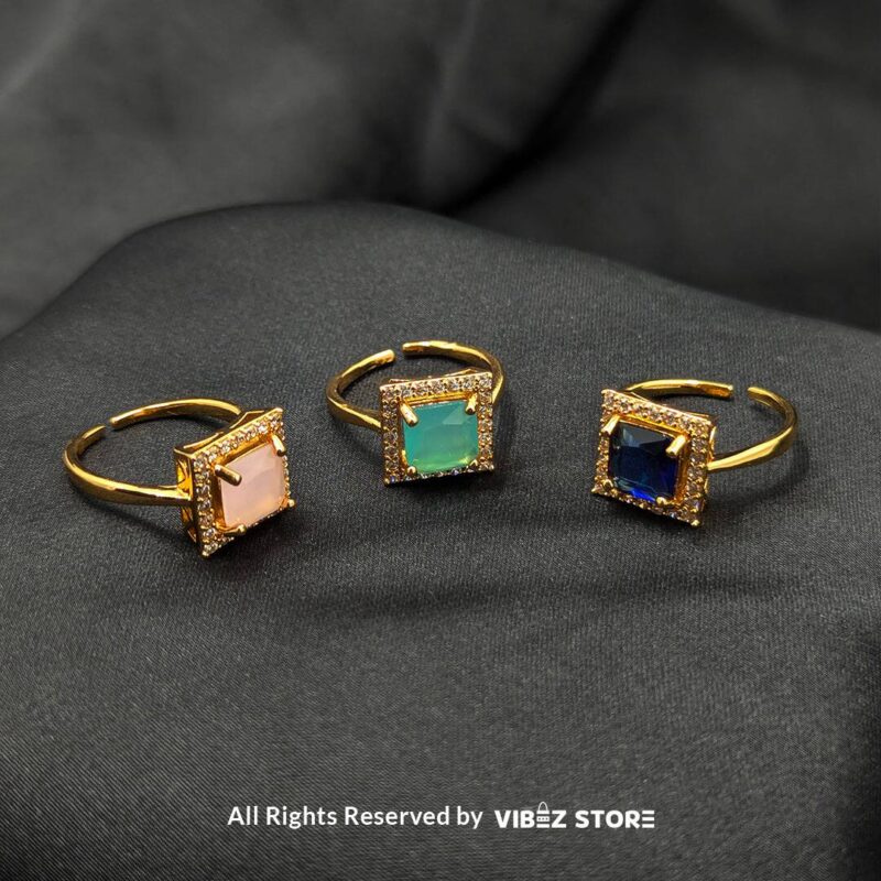 Gold-tone adjustable rings with square gemstones in rose pink, aqua blue, and sapphire variations, elegantly displayed by Vibez Store.